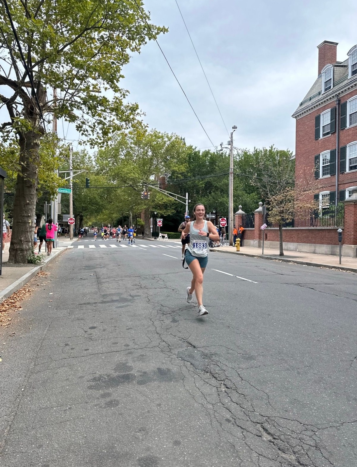Rosie mid-race, running down a tree-lined street.