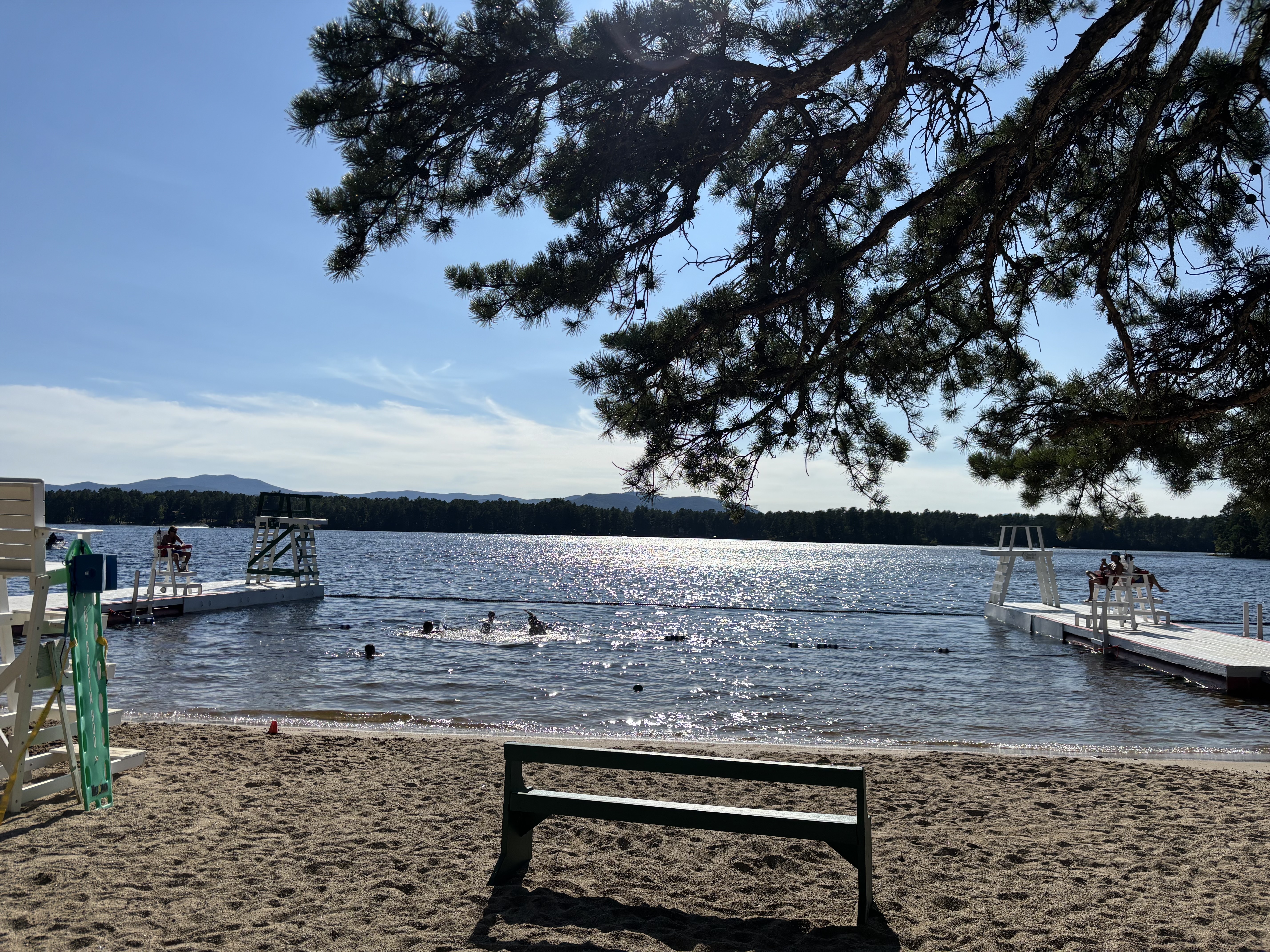 A lake beach with lifeguard docks and mountains in the distance.